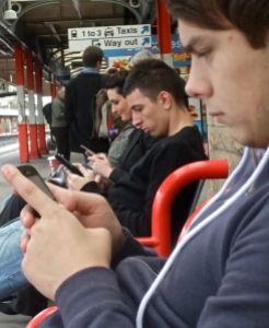 Three people sat immersed in their mobile communications devices, Lancaster railway station, 11/10/11